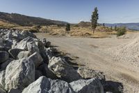 there is a bike rider on a paved dirt road through rocky area near a mountain