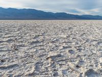 a barren area is full of dirt and rocks and mountains in the distance are many clouds