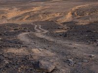 a truck on a dirt road in the desert with rocks and stones on the ground