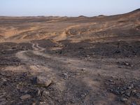 a truck on a dirt road in the desert with rocks and stones on the ground