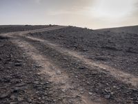 a truck on a dirt road in the desert with rocks and stones on the ground