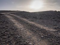 a truck on a dirt road in the desert with rocks and stones on the ground