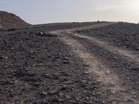 a truck on a dirt road in the desert with rocks and stones on the ground