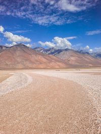 the desert is full of small rocks and a mountain range in the background with clouds in the sky