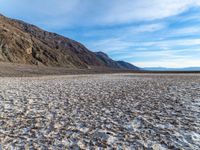 a view from a vast desert with mountains behind it in the desert, snow covered ground