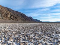 a view from a vast desert with mountains behind it in the desert, snow covered ground