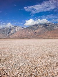 an open plain with snow capped mountains in the distance in the desert at sunset time