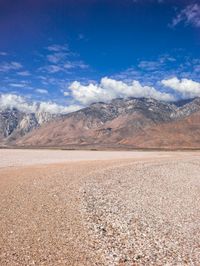 a very empty plain with no water on it, and mountains in the distance below