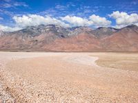 a lone bench is set in the middle of an empty desert plain with mountains in the background