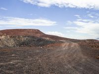 the red dirt and gravel is in the dirt road of an arid area with the mountains in the distance