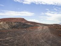 the red dirt and gravel is in the dirt road of an arid area with the mountains in the distance