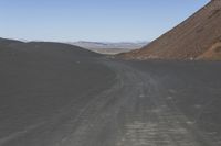 an empty road in the desert by the mountain range in the distance is the blue sky