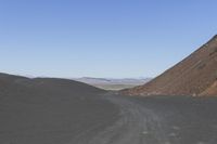 an empty road in the desert by the mountain range in the distance is the blue sky