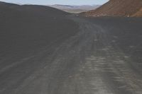 an empty road in the desert by the mountain range in the distance is the blue sky