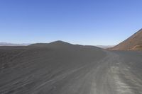 an empty road in the desert by the mountain range in the distance is the blue sky