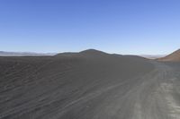 an empty road in the desert by the mountain range in the distance is the blue sky