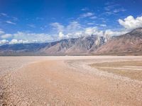 a very large dry body of water near mountains in the background area under blue skies