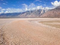 a very large dry body of water near mountains in the background area under blue skies