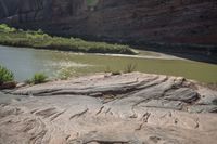 a couple of horses graze on the rock near a river shore area in colorado