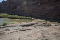 a couple of horses graze on the rock near a river shore area in colorado