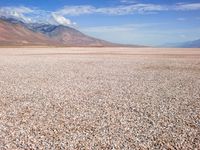 a view of a vast barren plain, with a mountain range in the distance behind