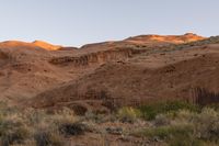 a man rides a horse through the valley in the desert with red cliffs in the background