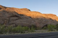 a man rides a horse through the valley in the desert with red cliffs in the background