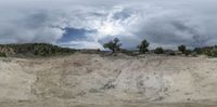 a photo of a view from a distance of sand and trees, with dark clouds in the background