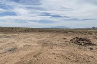 the large dirt field has rocks stacked up on top of it and mountains in the distance