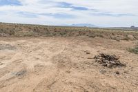 the large dirt field has rocks stacked up on top of it and mountains in the distance