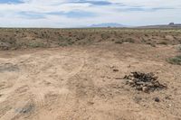 the large dirt field has rocks stacked up on top of it and mountains in the distance