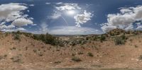 the panoramic view shows clouds in a blue sky above a canyon and forest