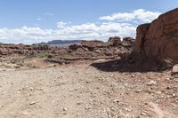 rocky ground with a dirt and rock slope in the distance, with a single motoble rider