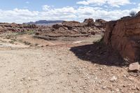 rocky ground with a dirt and rock slope in the distance, with a single motoble rider