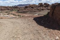 rocky ground with a dirt and rock slope in the distance, with a single motoble rider