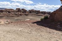 rocky ground with a dirt and rock slope in the distance, with a single motoble rider