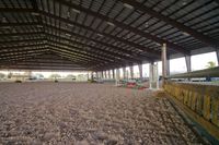 an indoor arena for horses, with horse stalls and equipment for a horse show or horseback riding