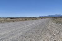 a dirt road with mountains in the background and a truck on the other side of it