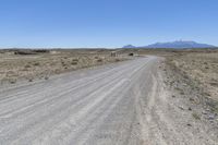 a dirt road with mountains in the background and a truck on the other side of it