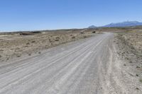 a dirt road with mountains in the background and a truck on the other side of it