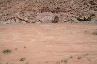 a dirt road through a desert plain with a mountain behind it and a clear blue sky in the background