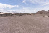 a dirt field in the middle of nowhere with rocks and dirt around it and a lone horse