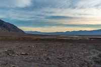 a vehicle is travelling through the dry terrain at sunset time in the desert near mountains