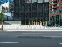 motion blurers as a car passes by a modern building in a city with a large metal screen behind