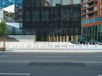 motion blurers as a car passes by a modern building in a city with a large metal screen behind