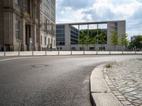 street sign sitting on side of road in front of some large buildings that have windows