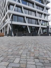 a modern office building has a stone courtyard in front of it as well as a bench with benches below