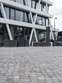 a modern office building has a stone courtyard in front of it as well as a bench with benches below