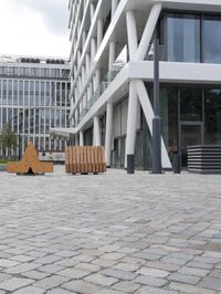 a modern office building has a stone courtyard in front of it as well as a bench with benches below