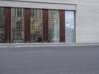 a person wearing blue jeans is riding a motorcycle outside of a building with brown windows